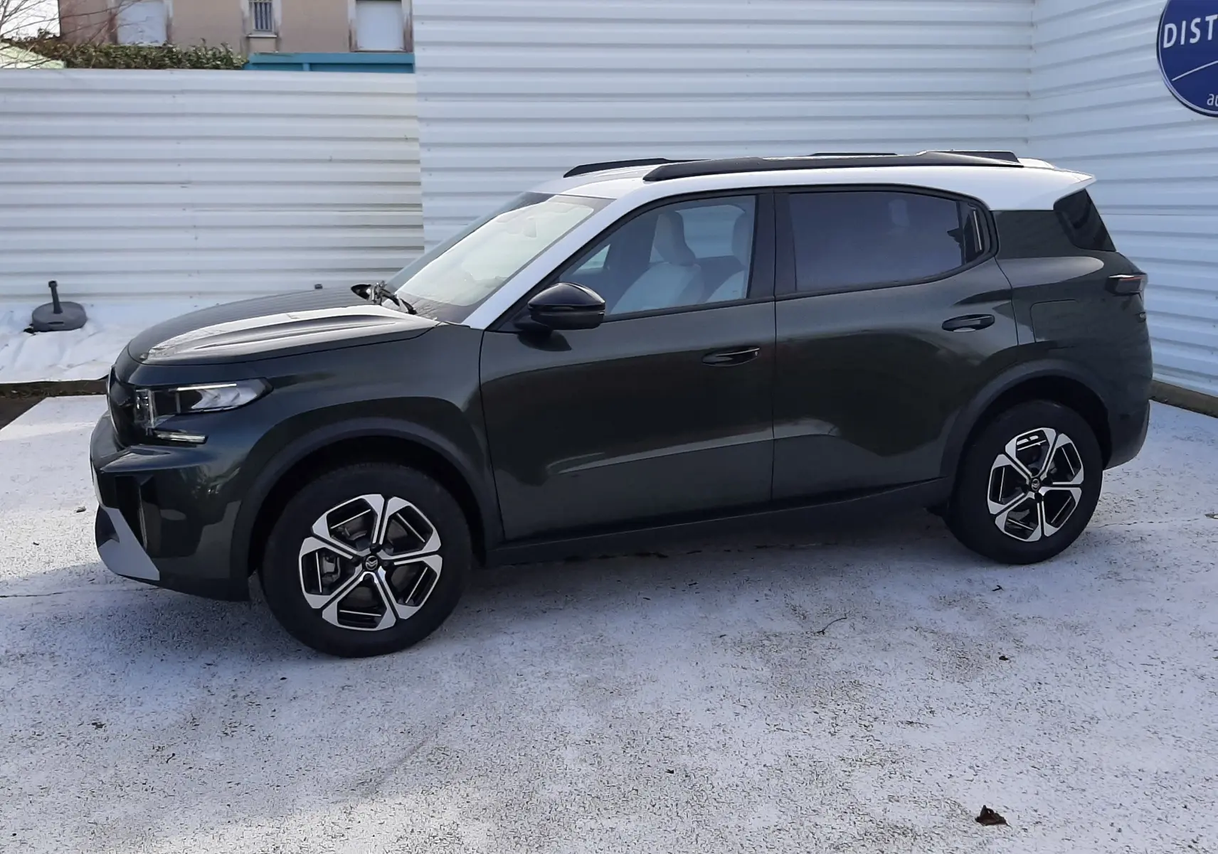 Vue de profil côté gauche d'un Citroën C3 Aircross hybride 2026 vert Montana avec toit blanc opale et jantes bi-ton.