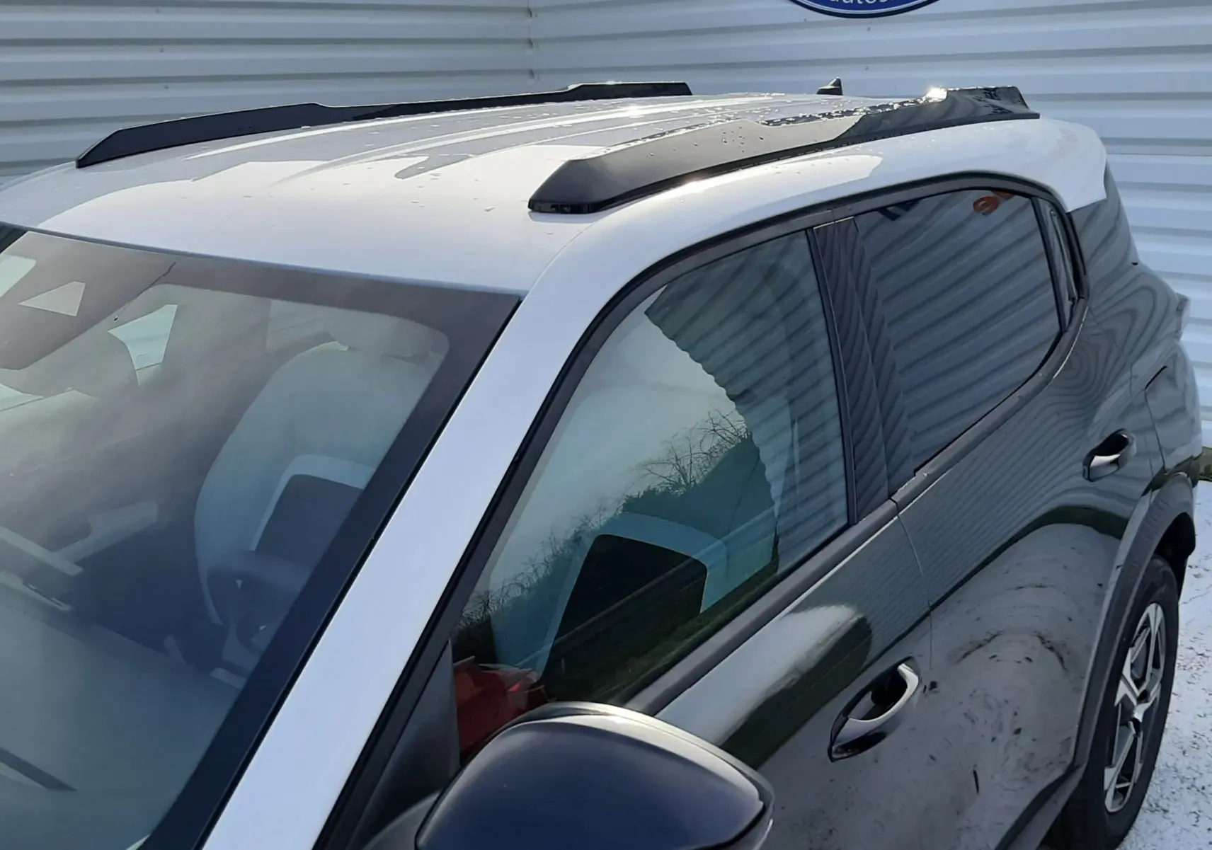 Vue 3/4 avant droit du Citroën C3 Aircross hybride 2026 vert Montana avec toit blanc opale et barres de toit noires.