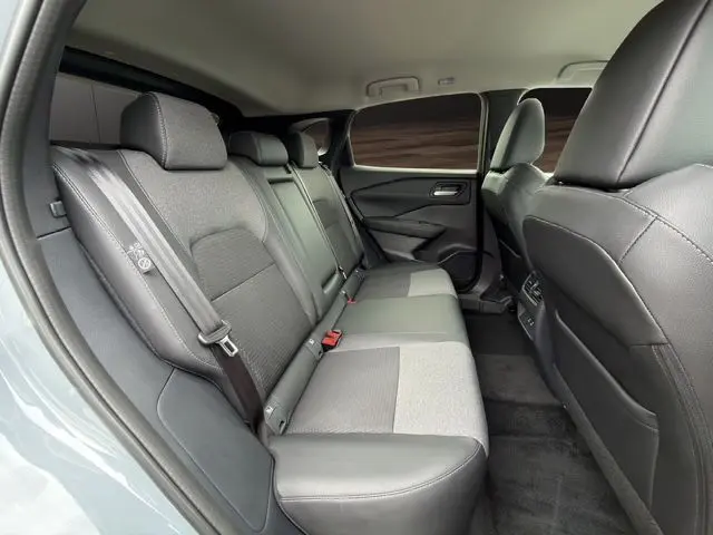 Vue intérieure côté gauche des sièges arrière en tissu gris et cuir noir du Nissan Qashqai 2025 Ceramic Grey avec hayon motorisé.