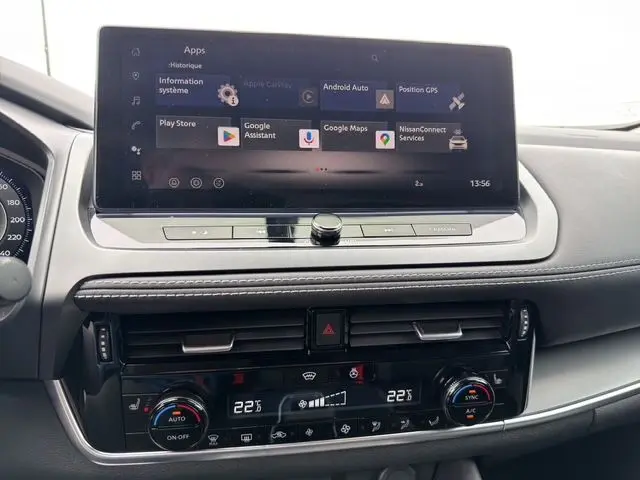 Vue rapprochée de la console centrale du Nissan Qashqai 2025 avec écran tactile et commandes de climatisation, intérieur noir.