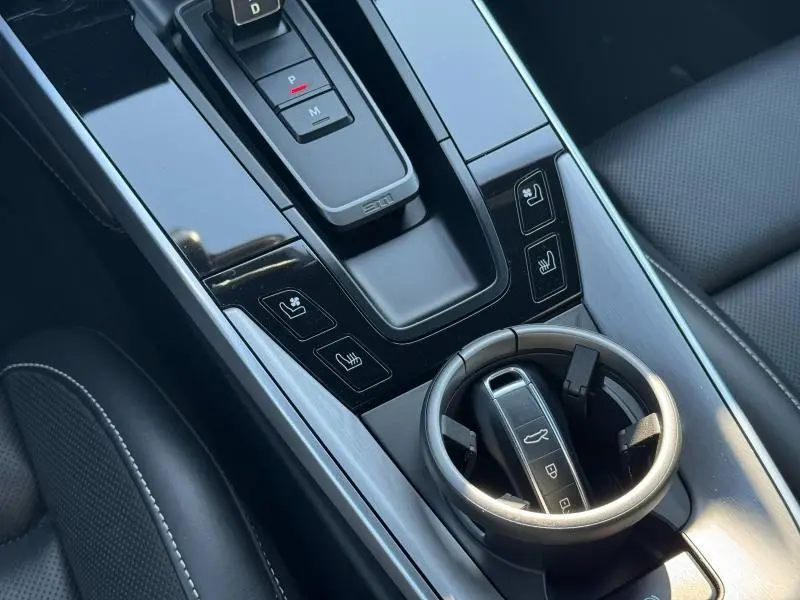 Vue rapprochée de la console centrale noire brillante d'une Porsche 911 Turbo S 2020 avec levier de vitesses et porte-gobelets.
