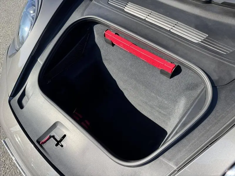 Vue plongeante sur le coffre avant ouvert d'une Porsche 911 Turbo S grise, avec un triangle de signalisation rouge visible.