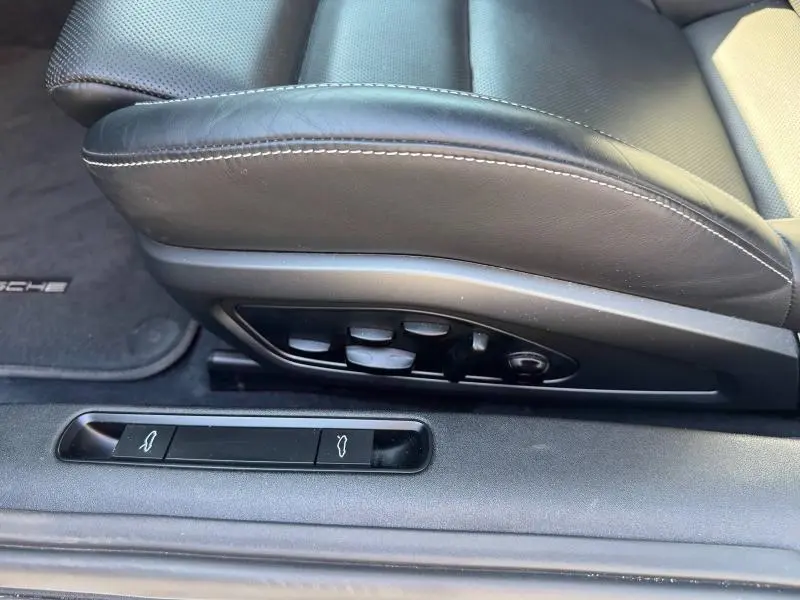 Gros plan sur le siège conducteur en cuir noir avec commandes électriques et boutons d'ouverture des coffres d'une Porsche 911 Turbo S 2020.