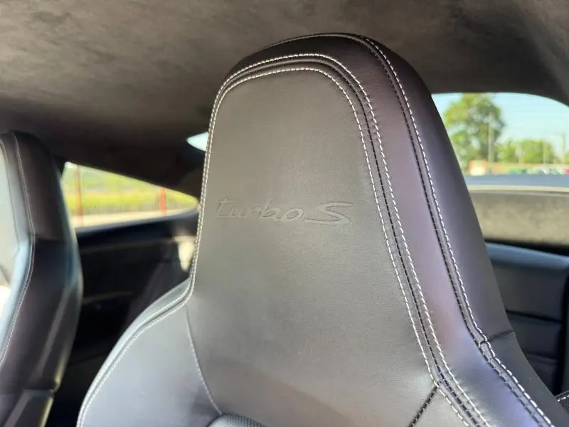 Gros plan sur l'appui-tête en cuir noir avec inscription "turbo S" en relief dans l'habitacle d'une Porsche 911 Turbo S.