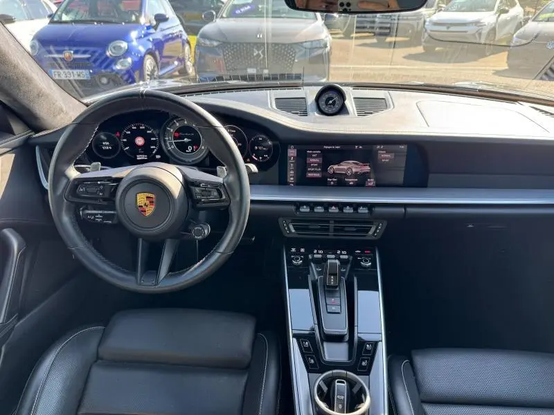 Vue intérieure avant de la Porsche 911 Turbo S 2020, tableau de bord et volant cuir noir avec écran tactile central allumé.