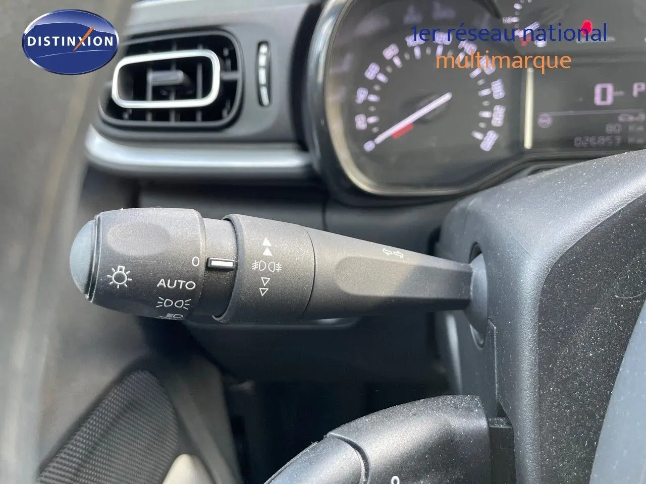 Gros plan sur la manette d'éclairage à gauche du volant dans l'habitacle d'une Citroën C3 gris platinium 2023.