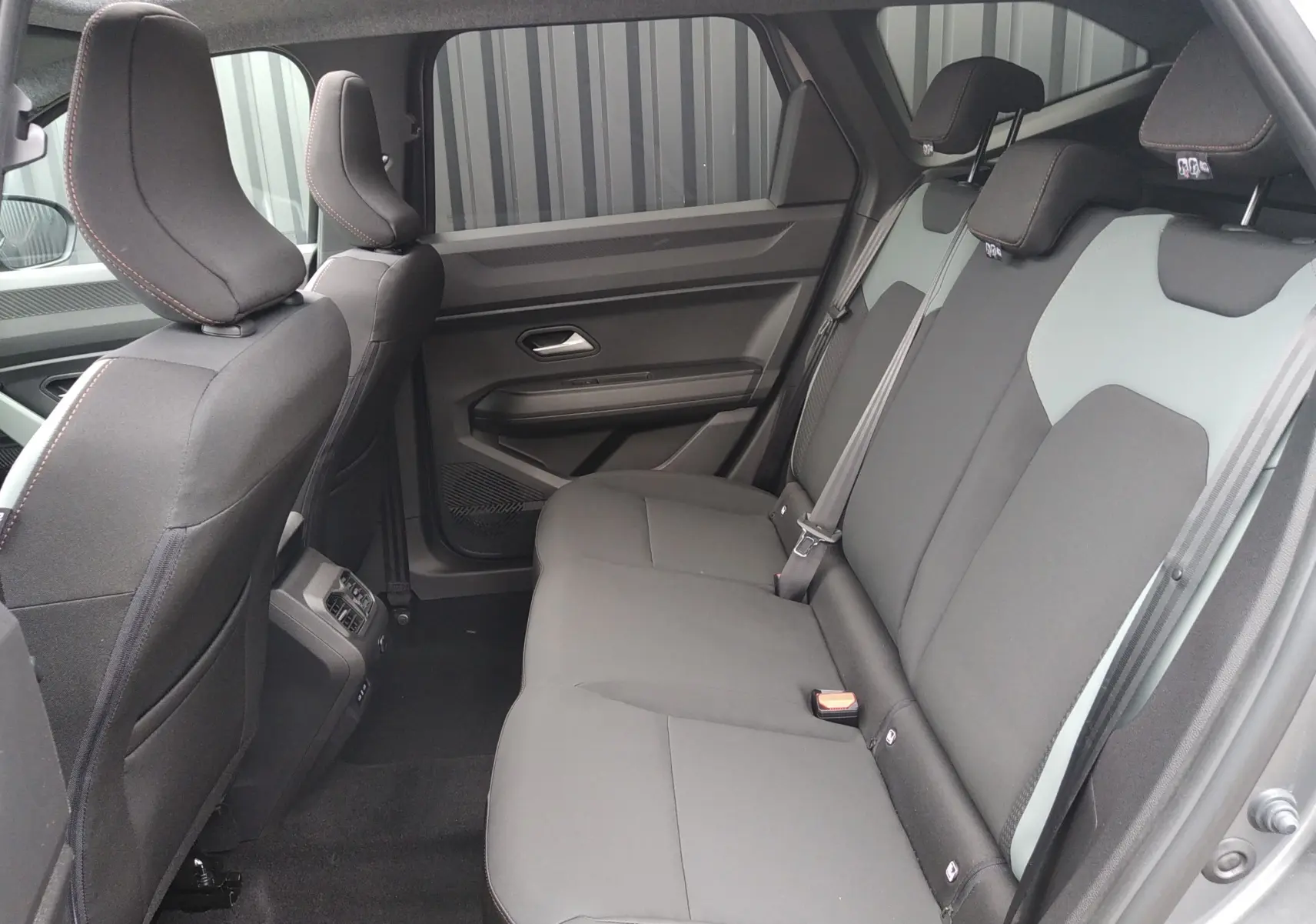Vue intérieure arrière côté droit du Dacia Bigster 2025, sièges tissu noir et gris schiste avec ceintures grises.