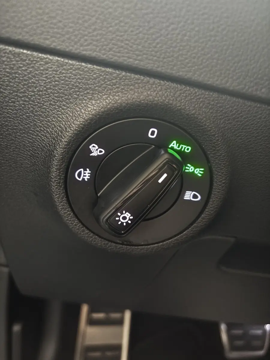 Gros plan sur la commande d'éclairage avec mode automatique activé dans l'habitacle noir du Skoda Karoq 2025.