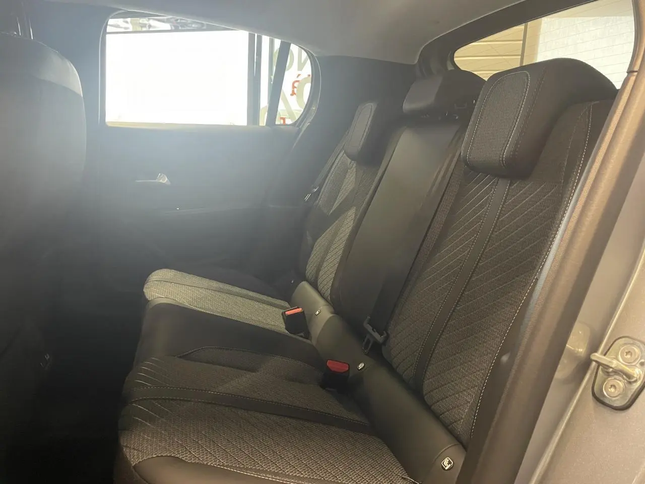 Banquette arrière vue côté droit de la Peugeot 208 gris Artense avec sellerie tissu et ceintures de sécurité visibles.
