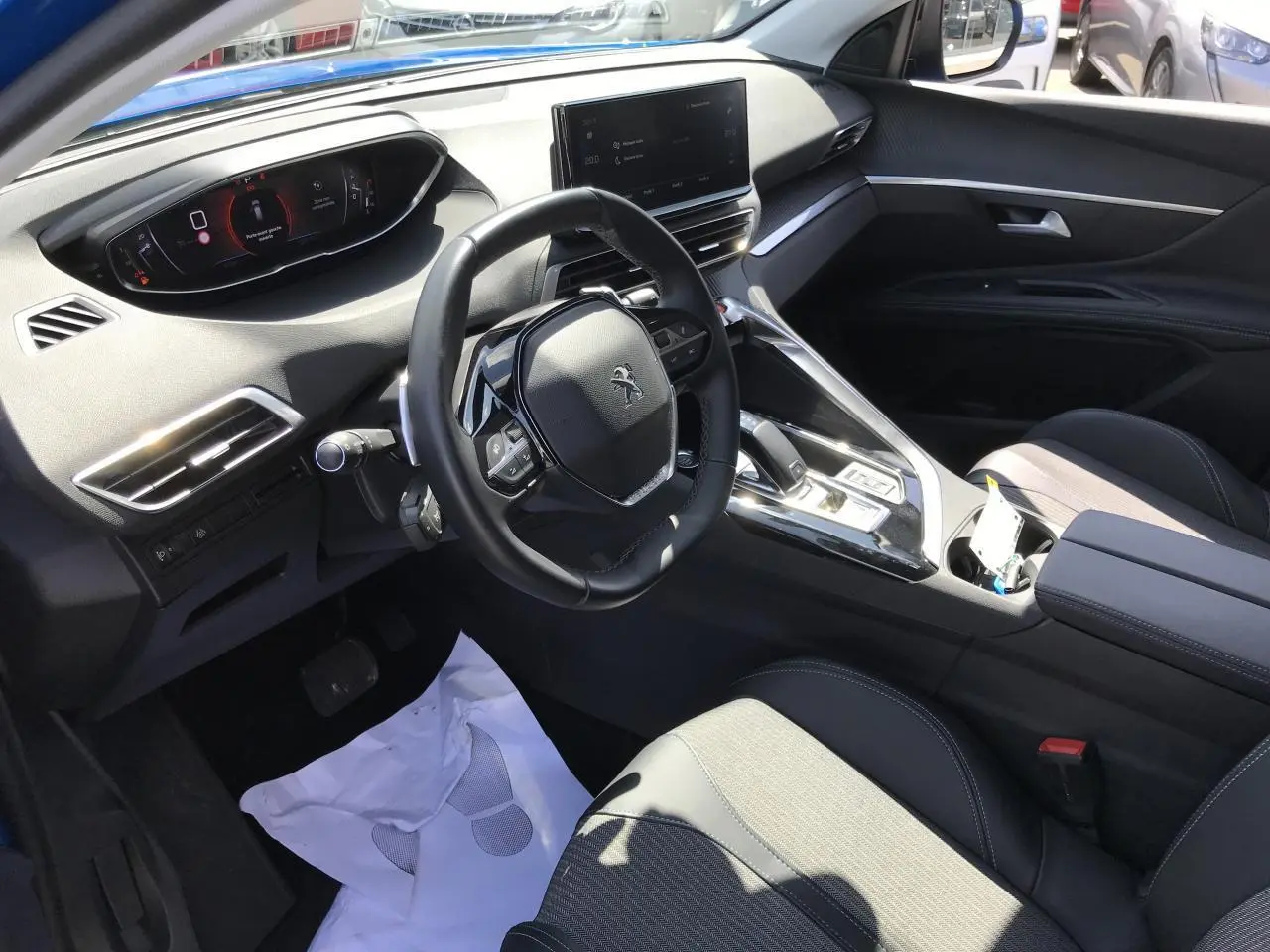 Vue intérieure côté conducteur du Peugeot 3008 2022 bleu Iron, avec volant compact et écran tactile central.