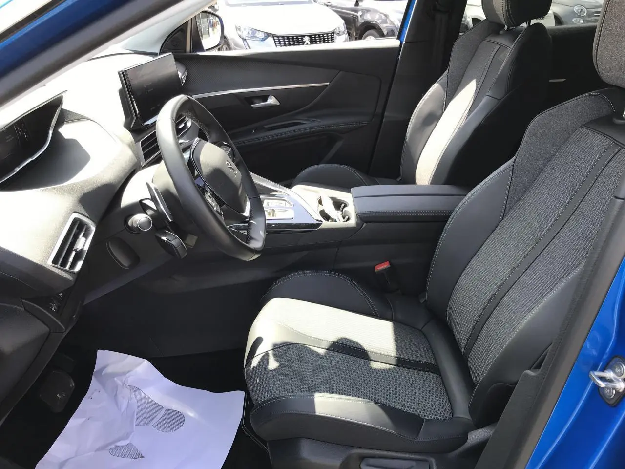 Vue intérieure côté conducteur du Peugeot 3008 bleu Iron 2022, mettant en valeur les sièges TEP et tissu et le volant cuir fleur.