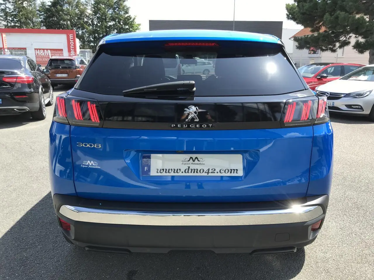 Vue arrière d'un Peugeot 3008 bleu Iron avec feux arrière à griffes rouges et bandeau noir brillant.