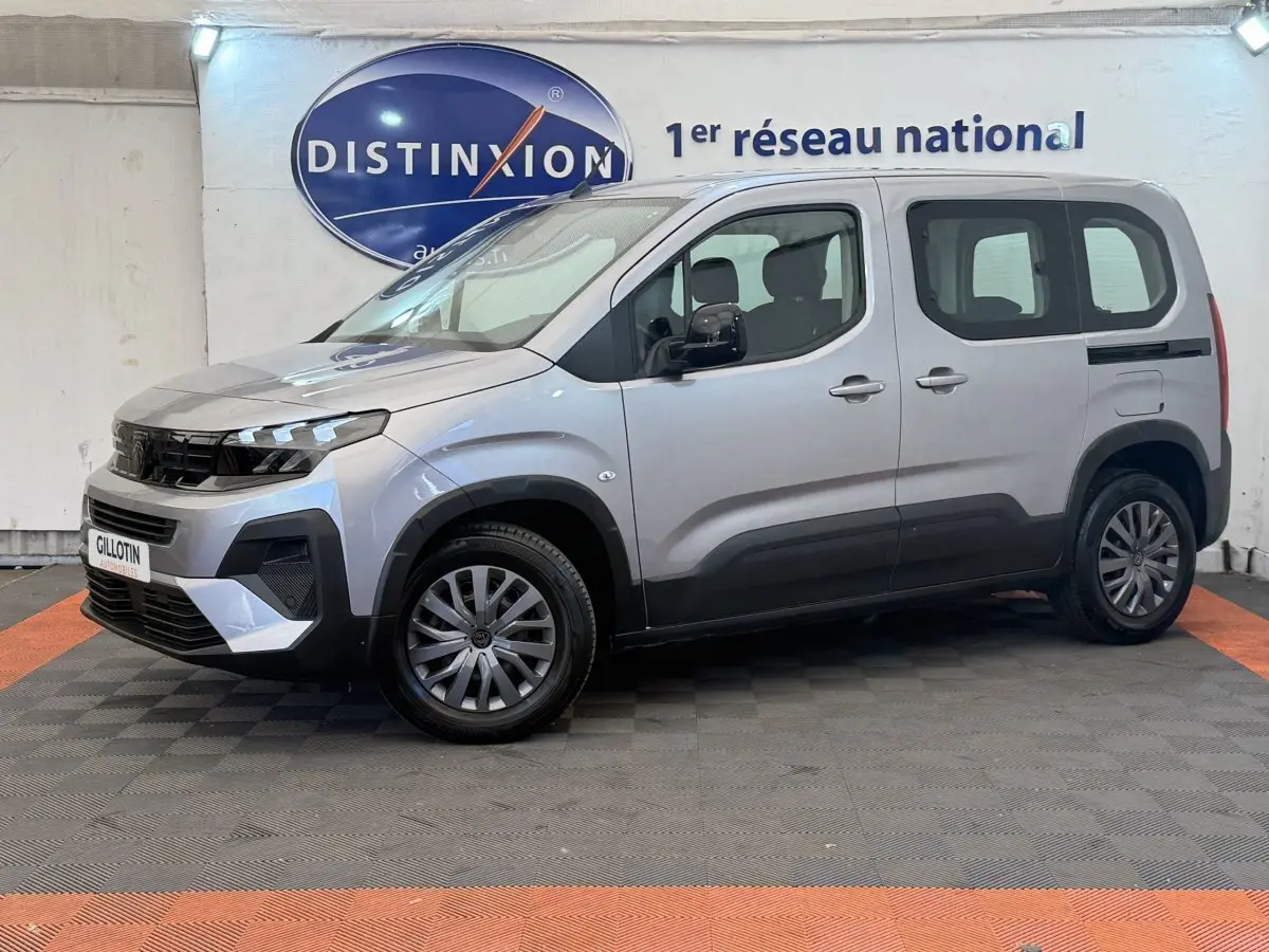 Peugeot Rifter gris clair vue de profil côté gauche, avec calandre noire et jantes alliage, en intérieur showroom.