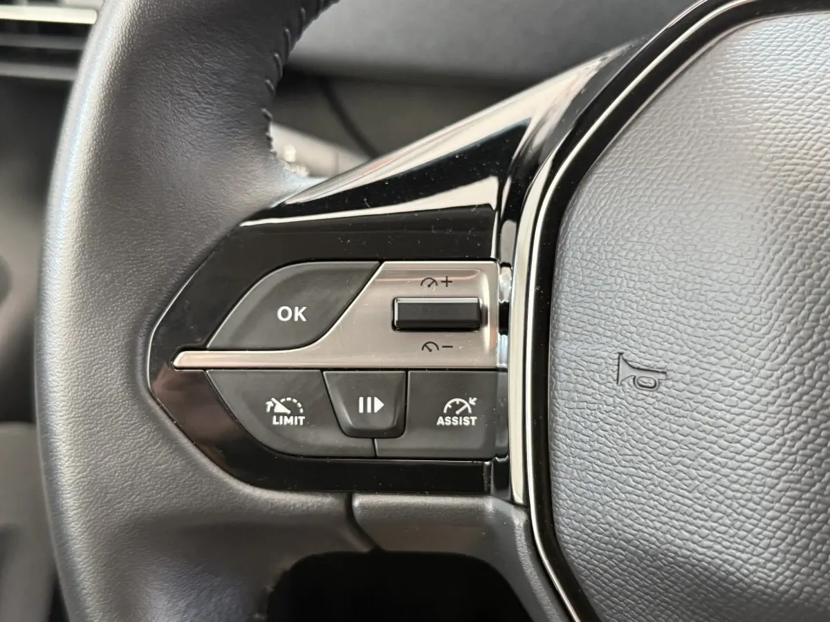 Gros plan sur le côté gauche du volant cuir noir du Peugeot Rifter 2024 avec commandes multifonctions intégrées.