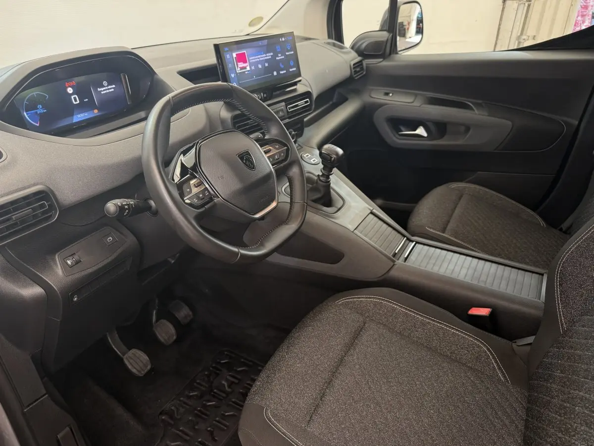 Vue intérieure côté conducteur du Peugeot Rifter 2024, volant cuir multifonctions et écran tactile central visible.