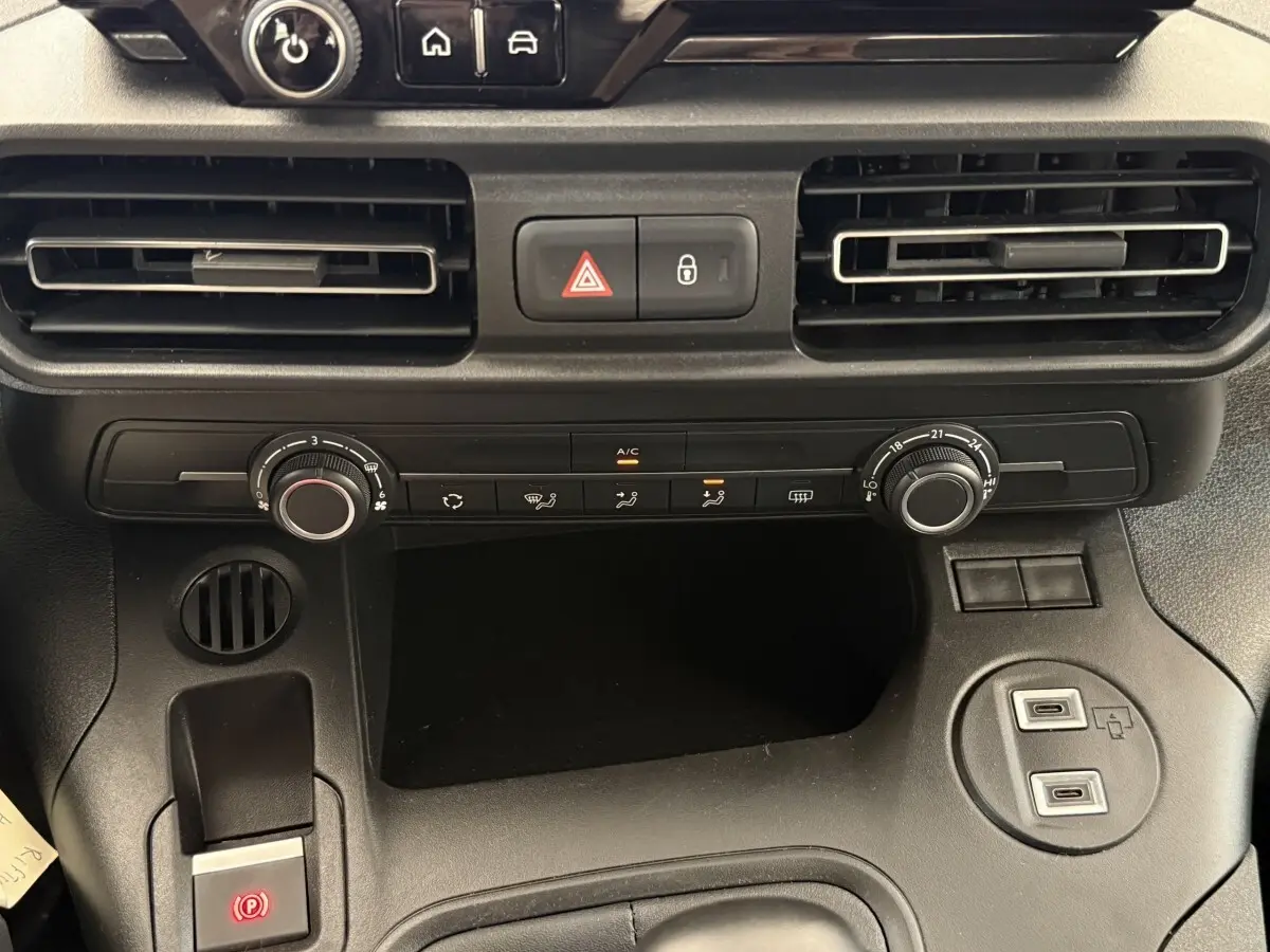 Gros plan sur la console centrale du Peugeot Rifter gris clair 2024, avec commandes climatisation et ports USB visibles.
