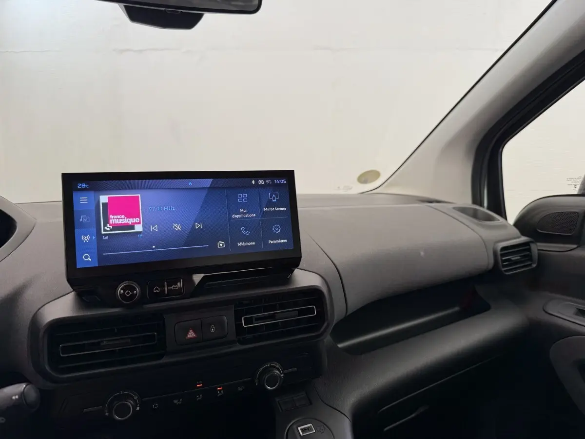 Vue intérieure côté passager du tableau de bord gris clair du Peugeot Rifter 2024 avec écran tactile central allumé.