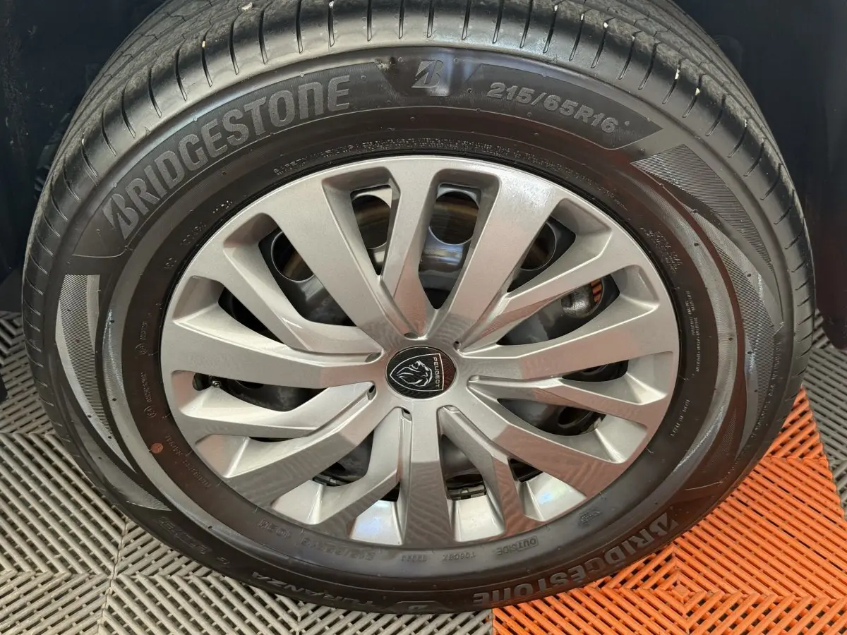 Gros plan sur la roue avant droite du Peugeot Rifter gris clair 2024 avec jante alliage et pneu Bridgestone.