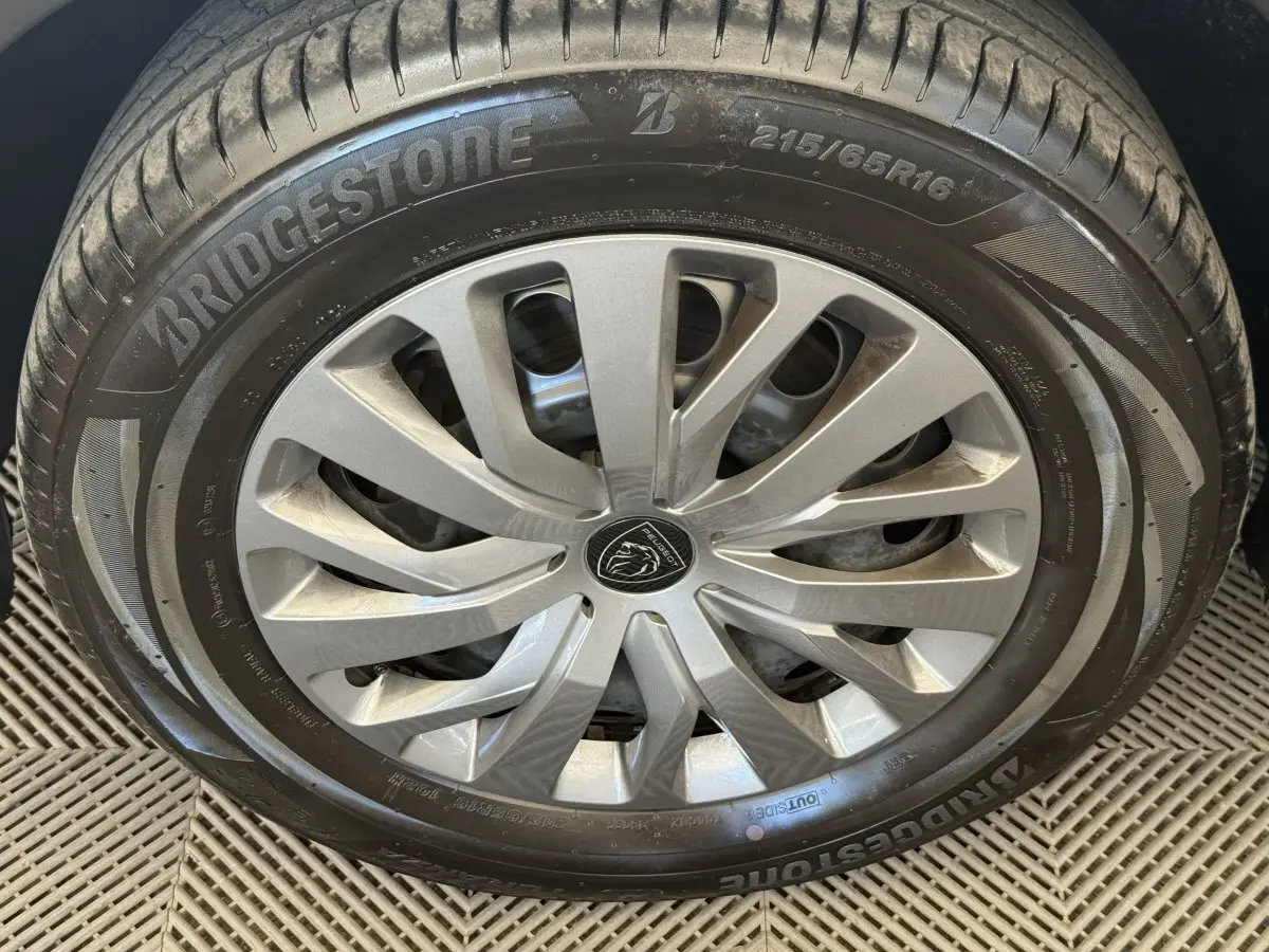 Gros plan sur la roue avant droite du Peugeot Rifter gris clair, jante alliage et pneu Bridgestone visible.
