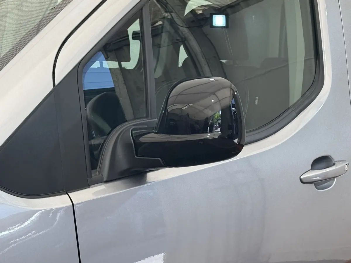 Vue rapprochée du rétroviseur noir côté gauche sur la porte gris clair du Peugeot Rifter 2024.