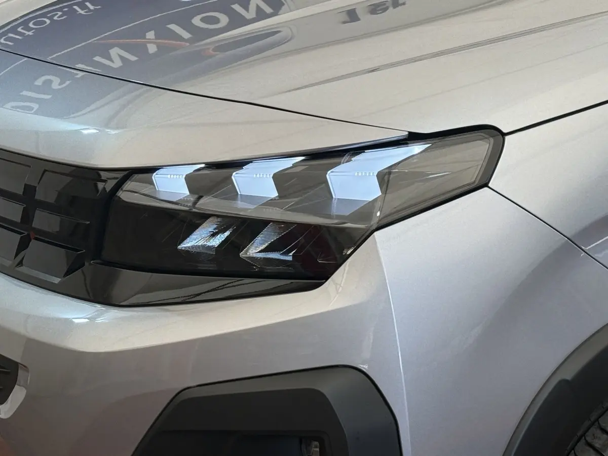 Gros plan sur le phare avant droit du Peugeot Rifter gris clair 2024 avec calandre noire et détails LED distinctifs.