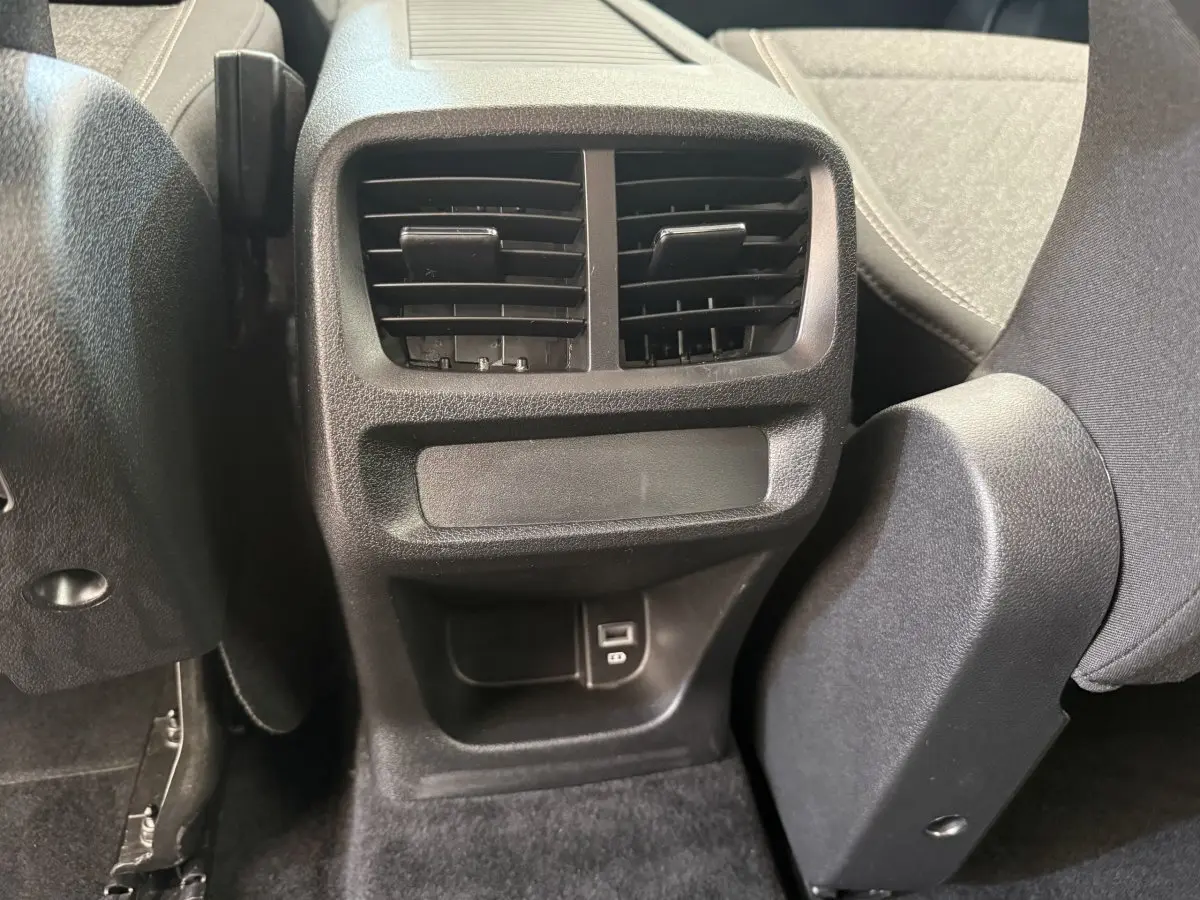 Détail de la console arrière noire avec bouches d’aération et prise USB du Peugeot Rifter gris clair 2024.