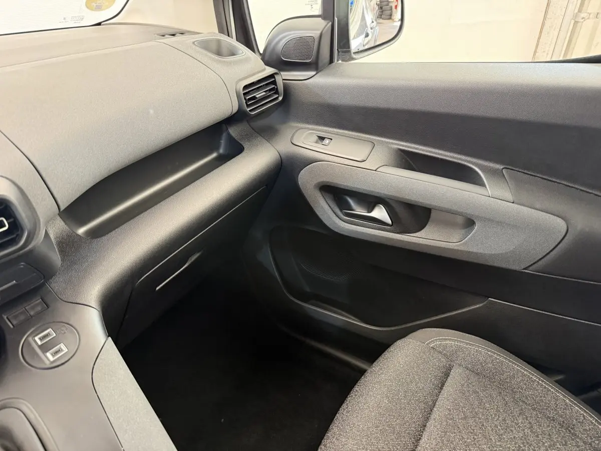 Vue intérieure côté passager du Peugeot Rifter 2024 gris clair, montrant la portière et le tableau de bord minimaliste.