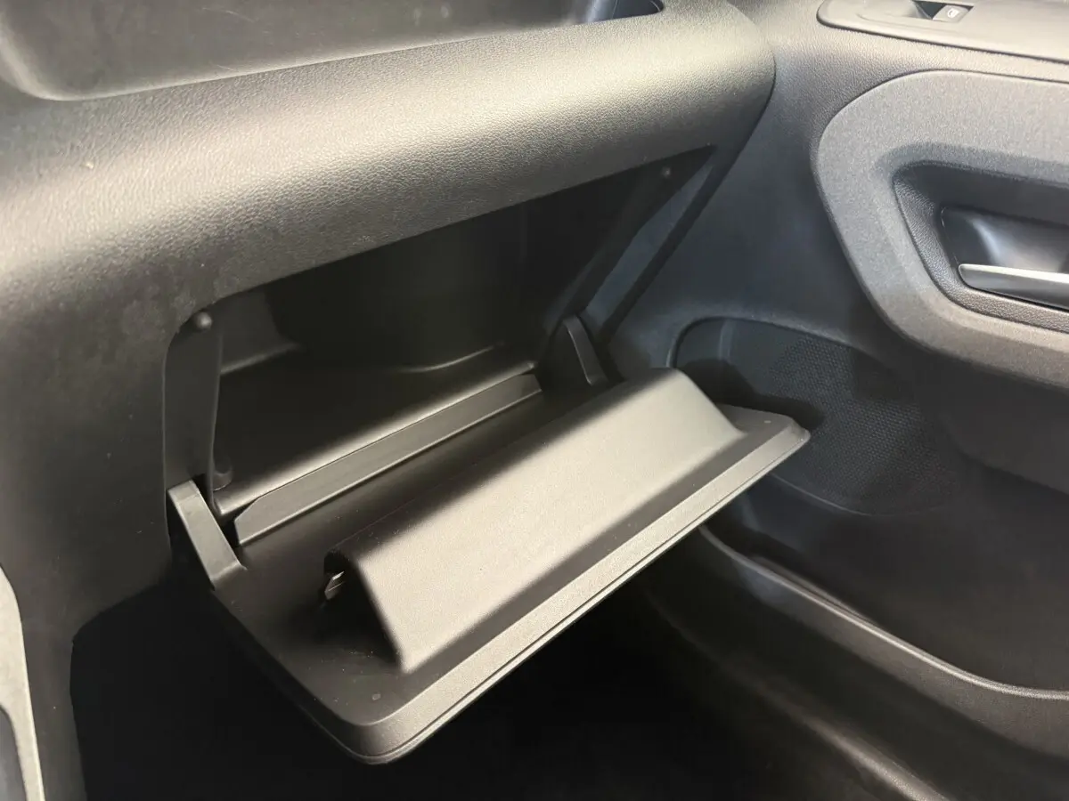 Vue rapprochée de la boîte à gants ouverte côté passager du Peugeot Rifter 2024, intérieur noir.