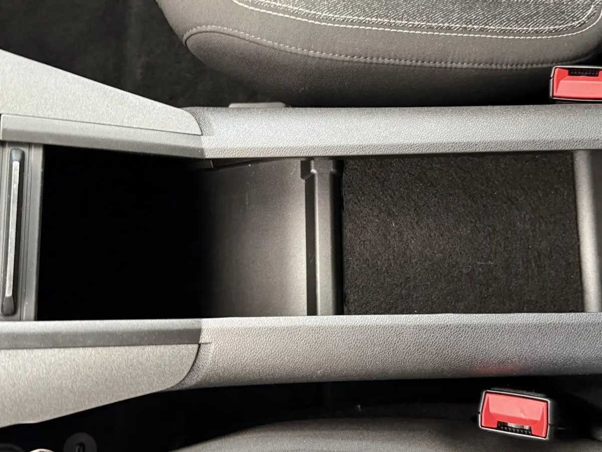 Vue rapprochée de la console centrale grise du Peugeot Rifter 2024 avec ouverture de rangement entre les sièges avant.