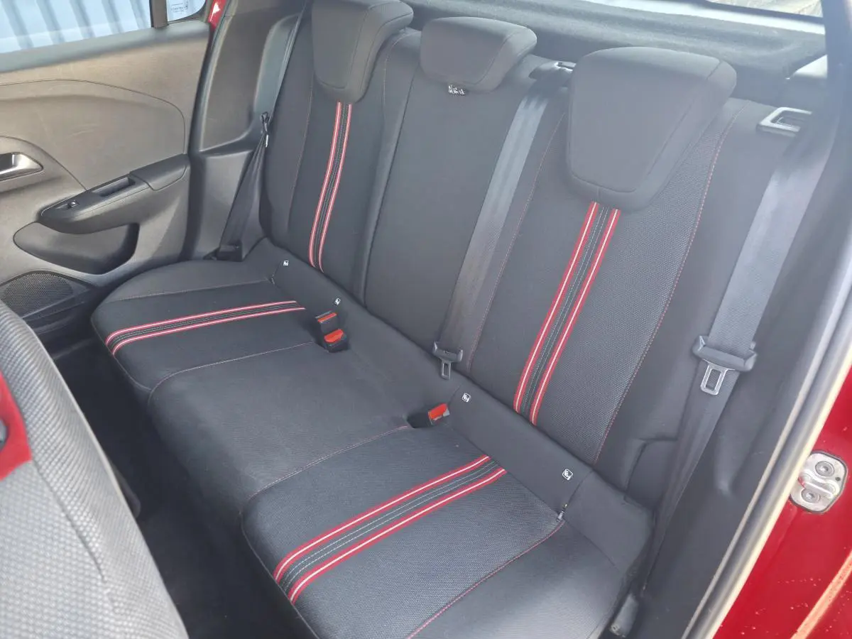 Vue intérieure côté droit de la banquette arrière noire avec bandes rouges sur une Opel Corsa rouge.