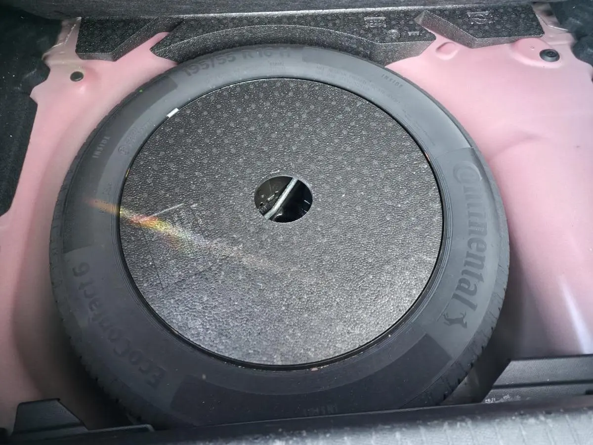 Roue de secours 16 pouces dans le coffre d'une Opel Corsa rouge, vue plongeante sur le pneu Continental.
