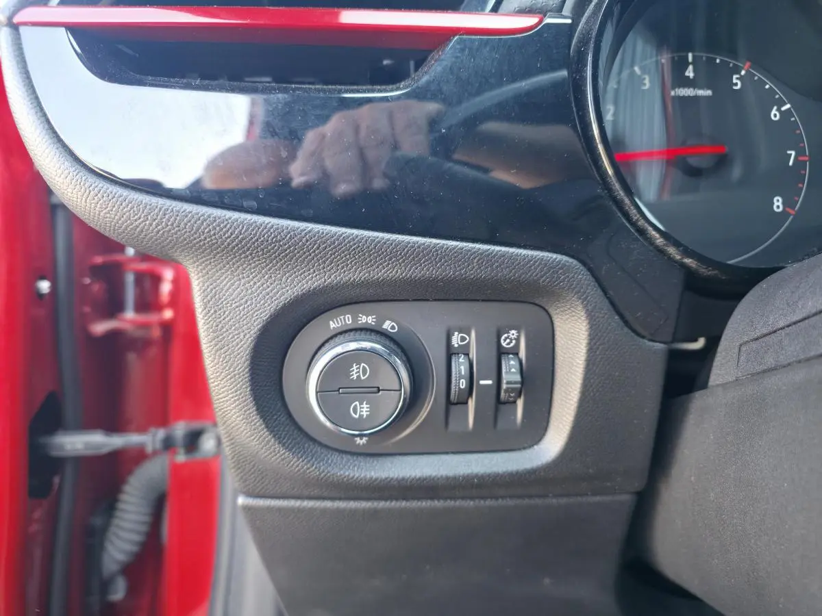 Détail des commandes d’éclairage côté gauche sur tableau de bord d’une Opel Corsa rouge 2020.