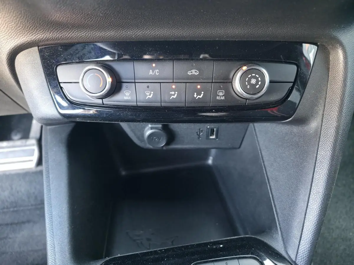 Vue rapprochée de la console centrale noire de l’Opel Corsa 1.2i Turbo avec commandes de climatisation et prise USB.