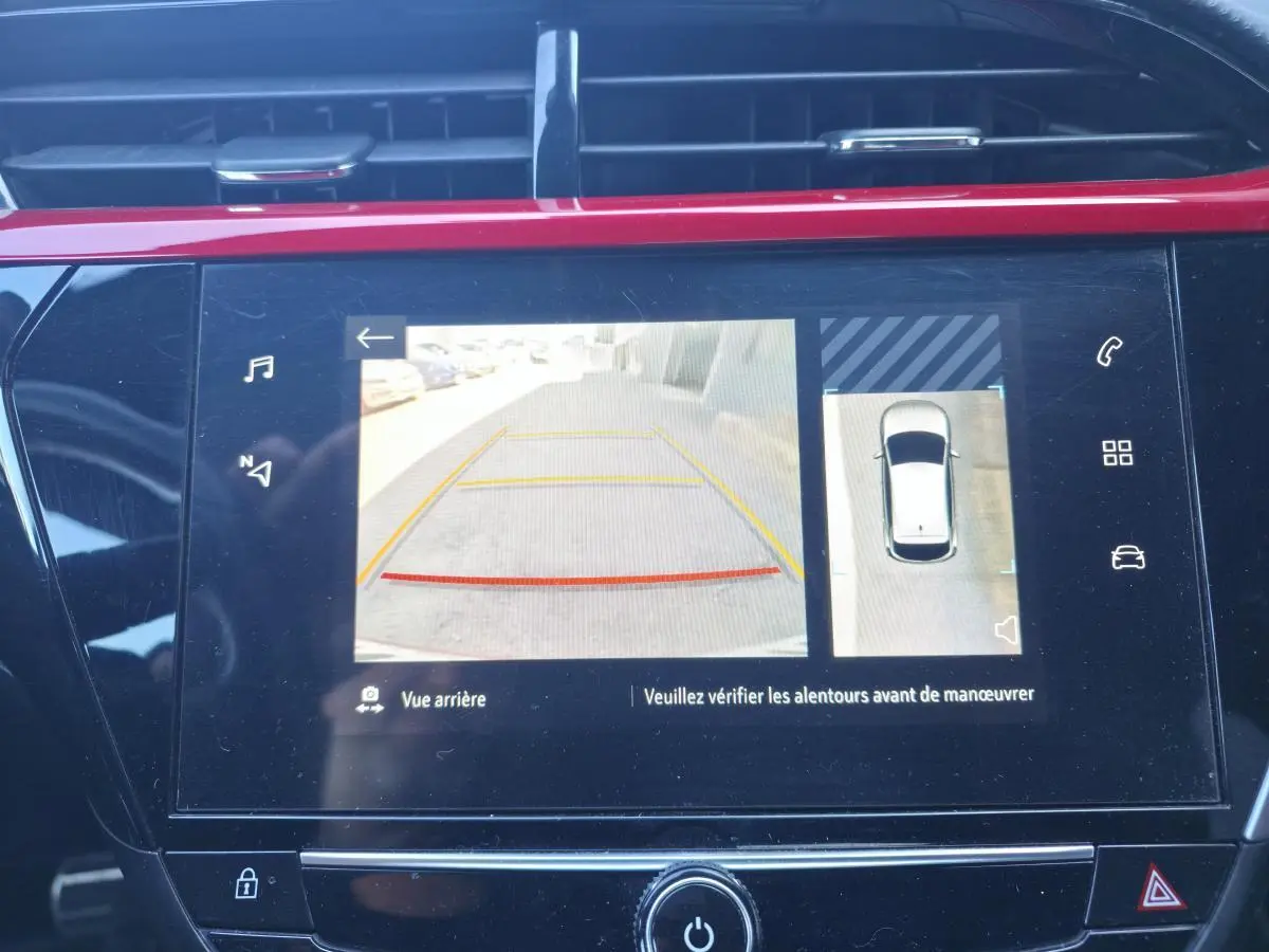 Écran tactile intérieur montrant la caméra de recul et la vue à 180° de l’Opel Corsa rouge en stationnement.