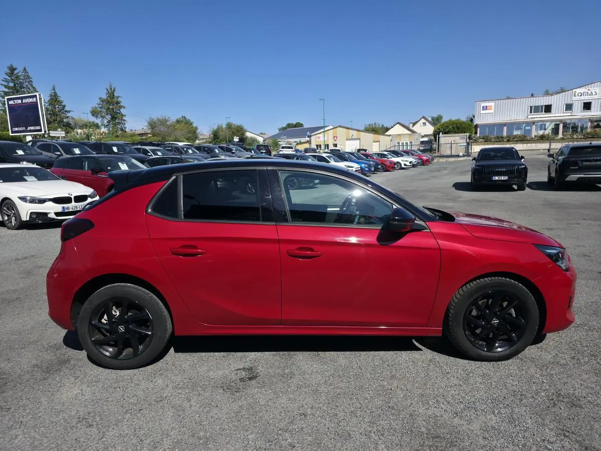 Opel Corsa rouge vue de profil côté gauche avec jantes noires et vitres arrière surteintées.
