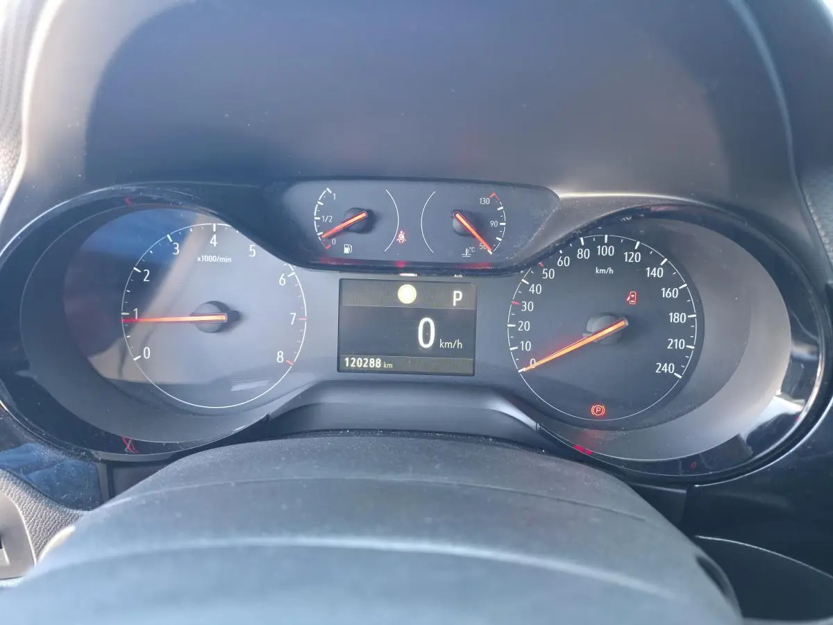 Vue rapprochée du tableau de bord de l'Opel Corsa rouge, affichant la vitesse à 0 km/h et le compteur moteur.