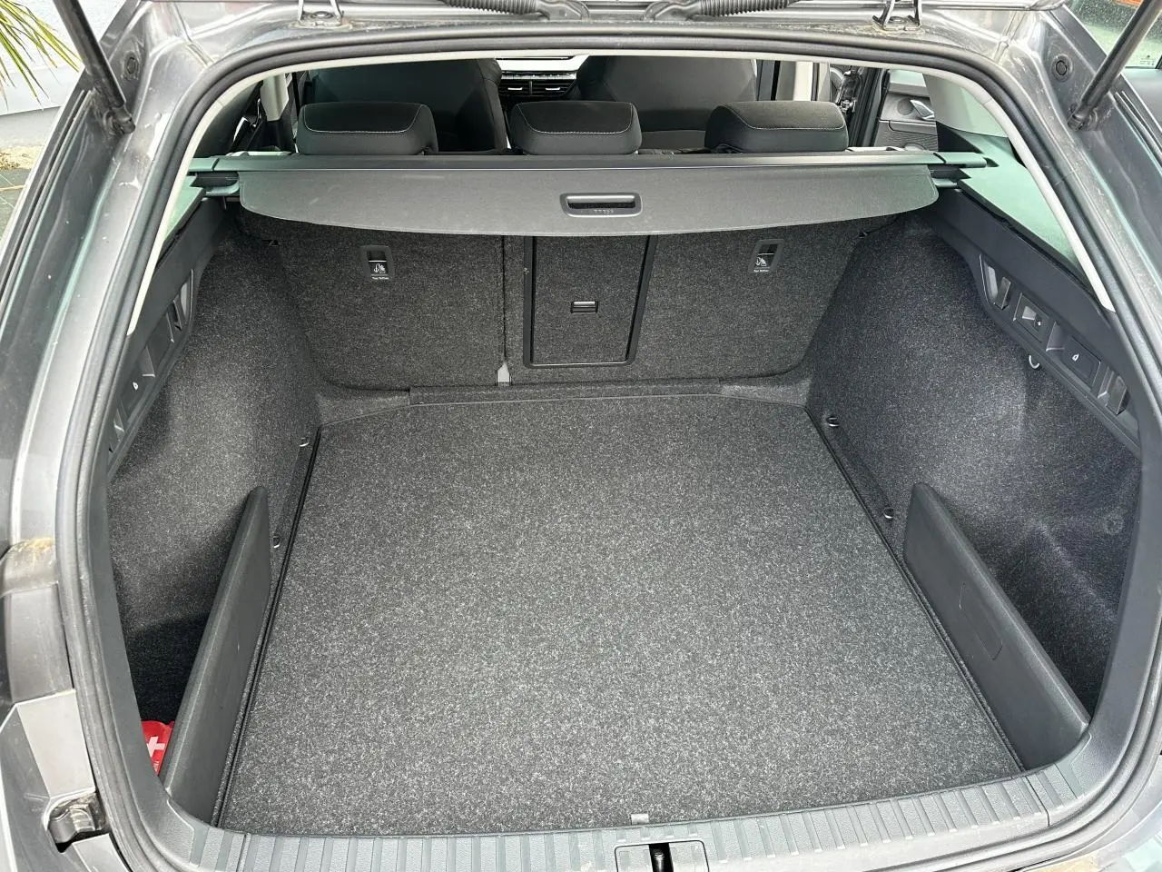 Coffre ouvert vu de l'arrière d'une Skoda Octavia Combi gris graphite, montrant un espace de chargement propre et spacieux.