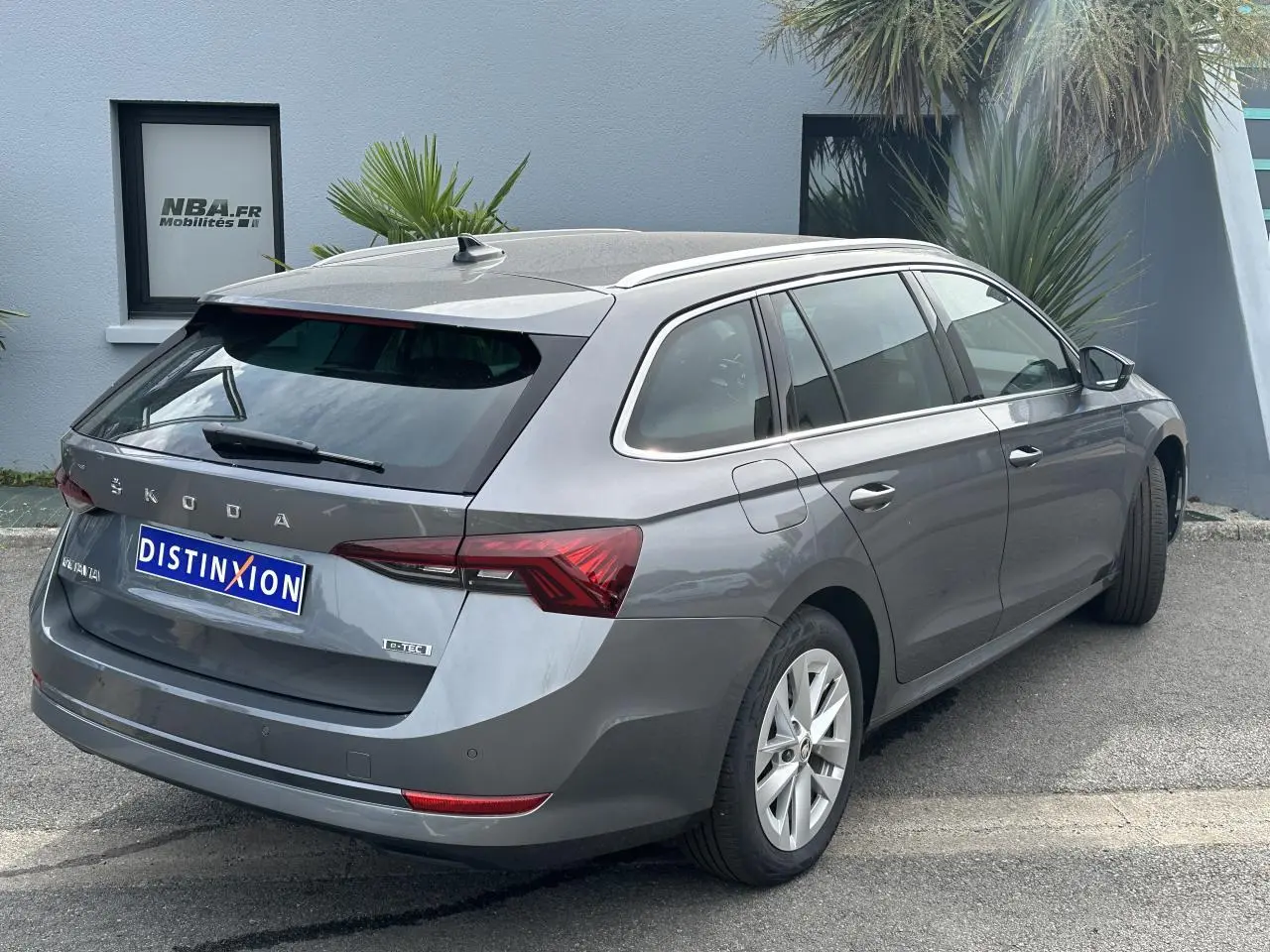 Vue 3/4 arrière droite d'une Skoda Octavia Combi gris graphite avec feux arrière LED et attelage amovible.