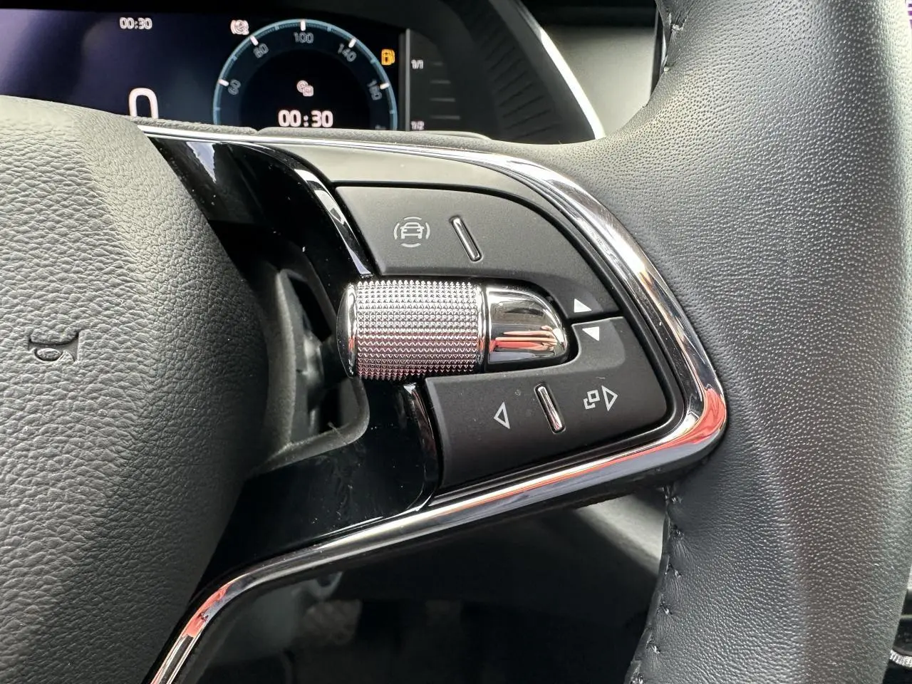 Gros plan sur les commandes chromées du volant cuir noir de la Skoda Octavia Combi 2024 avec tableau de bord numérique.