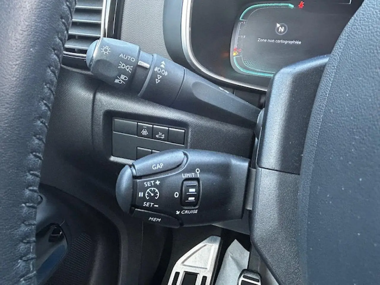 Gros plan sur les commandes de régulateur de vitesse et éclairage côté gauche du volant d'un Citroën C5 Aircross gris platinium.