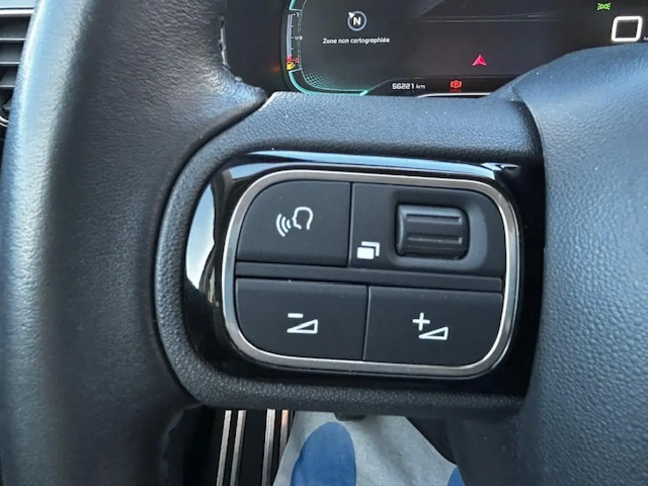 Gros plan sur les commandes au volant noir et chrome du Citroën C5 Aircross gris platinium, affichage numérique en arrière-plan.