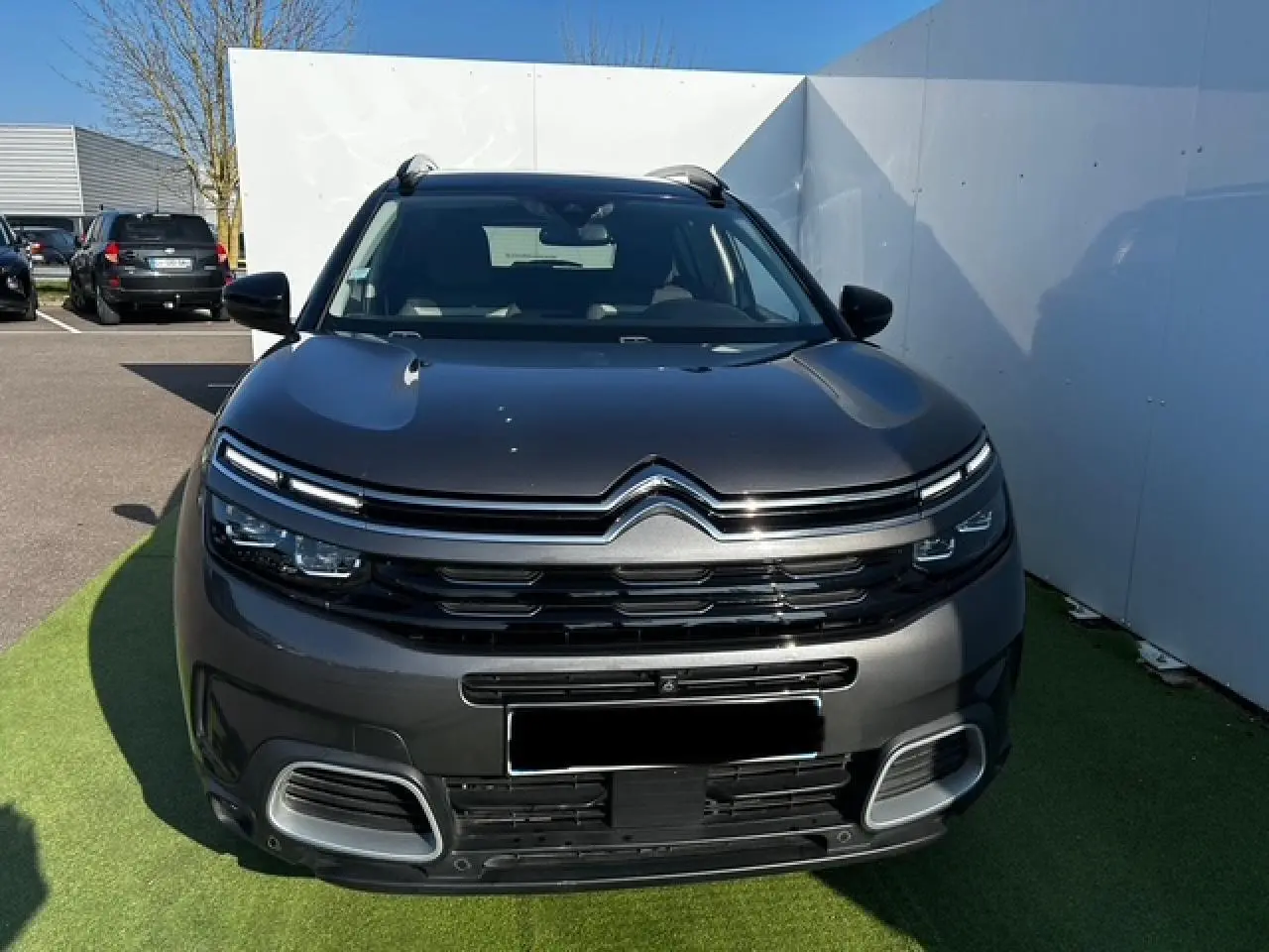 Vue frontale d'un Citroën C5 Aircross gris platinium métallisé avec calandre noire brillante et projecteurs LED.