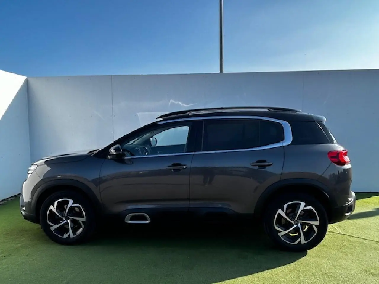 Profil côté gauche du Citroën C5 Aircross gris platinium métallisé avec jantes alliage 18 pouces et barres de toit noires.