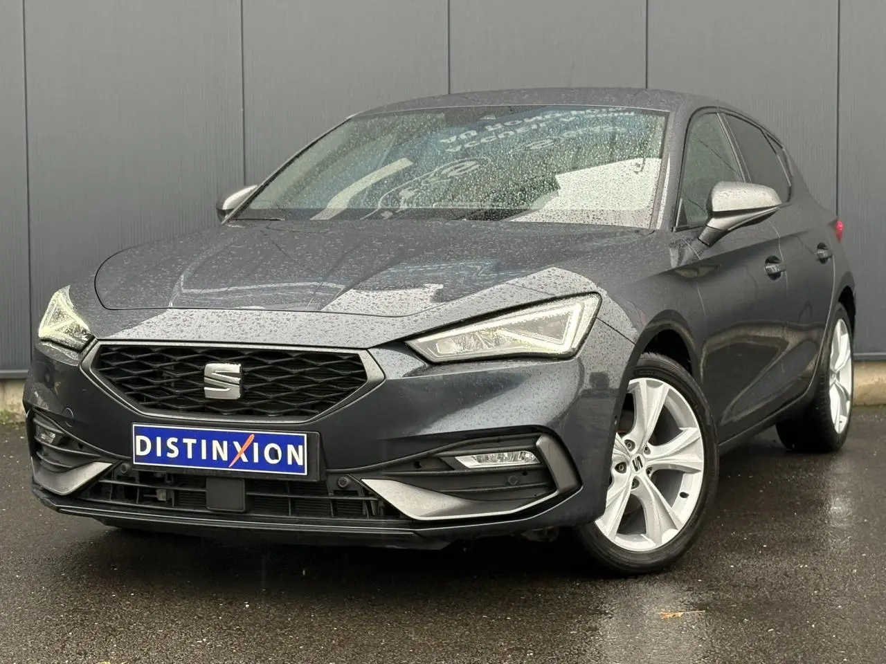 SEAT LEON 1.5 e-TSI 150 DSG7 FR gris magnétique en 3/4 avant droit sous la pluie avec jantes alliage 17 pouces.
