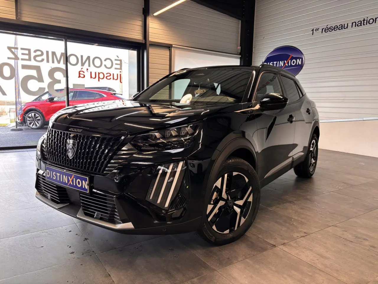 Peugeot 2008 noir en 3/4 avant droit, avec calandre noire et jantes alliage bi-ton dans un showroom.