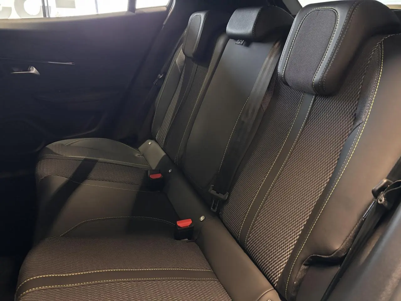 Vue latérale des sièges arrière noirs avec surpiqûres vertes du Peugeot 2008 Hybrid 2025.