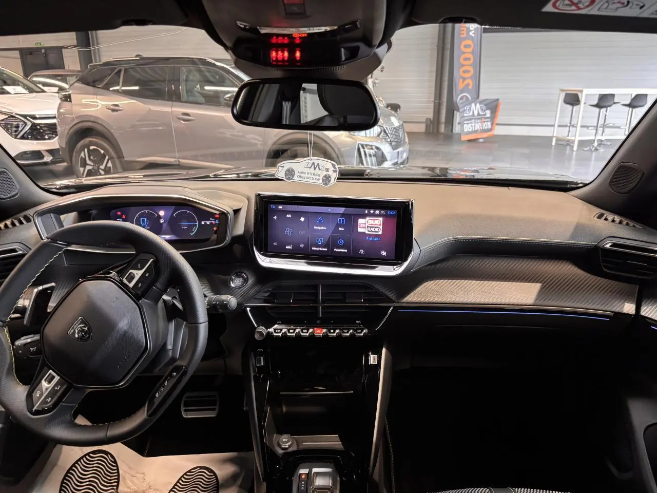 Vue intérieure avant du Peugeot 2008 noir avec tableau de bord numérique et écran tactile central lumineux.