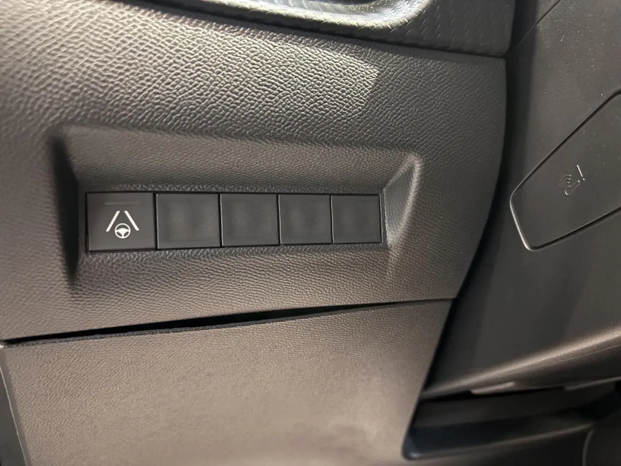 Boutons de commande noirs sur panneau intérieur côté gauche du Peugeot 2008 noir hybride 2025, avec symbole d'assistance au maintien de voie.