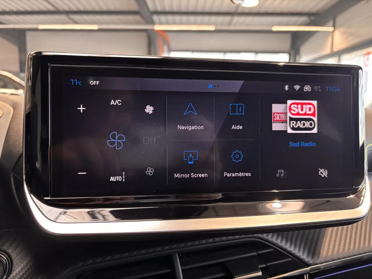 Écran tactile central du Peugeot 2008 noir, affichant les commandes de climatisation et navigation en intérieur lumineux.