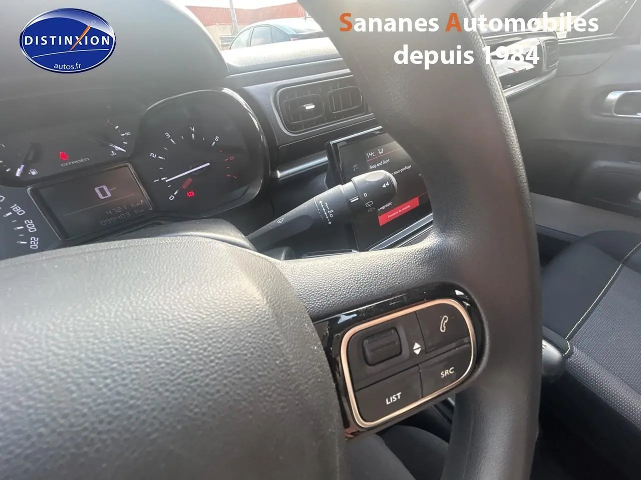 Vue intérieure centrée sur le volant avec commandes audio, tableau de bord et écran tactile de la Citroën C3 2023.